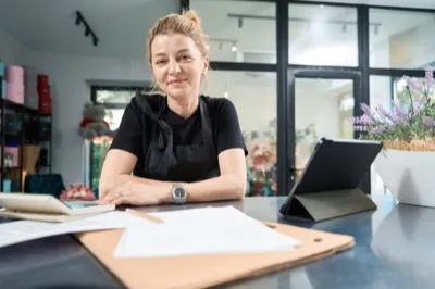 Small business owner at desk with papers and laptop